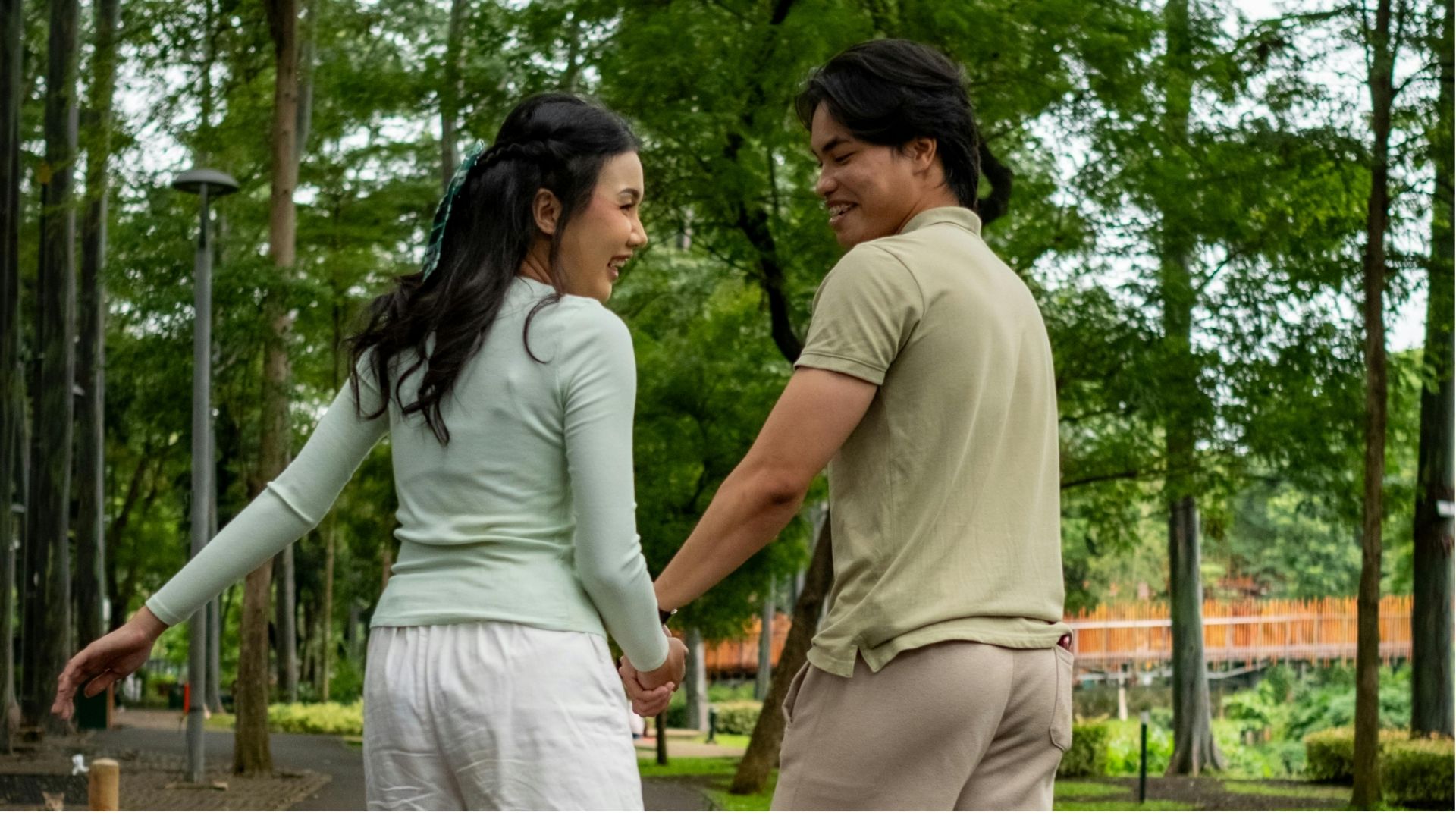 A couple holding hands on a walk through a bamboo garden